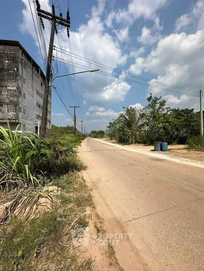 Scenic road view with adjacent building and lush greenery under a bright blue sky.