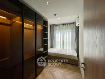 Modern bedroom with sleek wardrobe and large window, offering ample natural light and contemporary design.