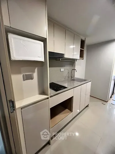Modern compact kitchen with sleek cabinetry and built-in appliances in a stylish apartment.