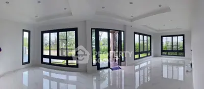 Spacious modern living room with large windows and glossy floors, offering abundant natural light.