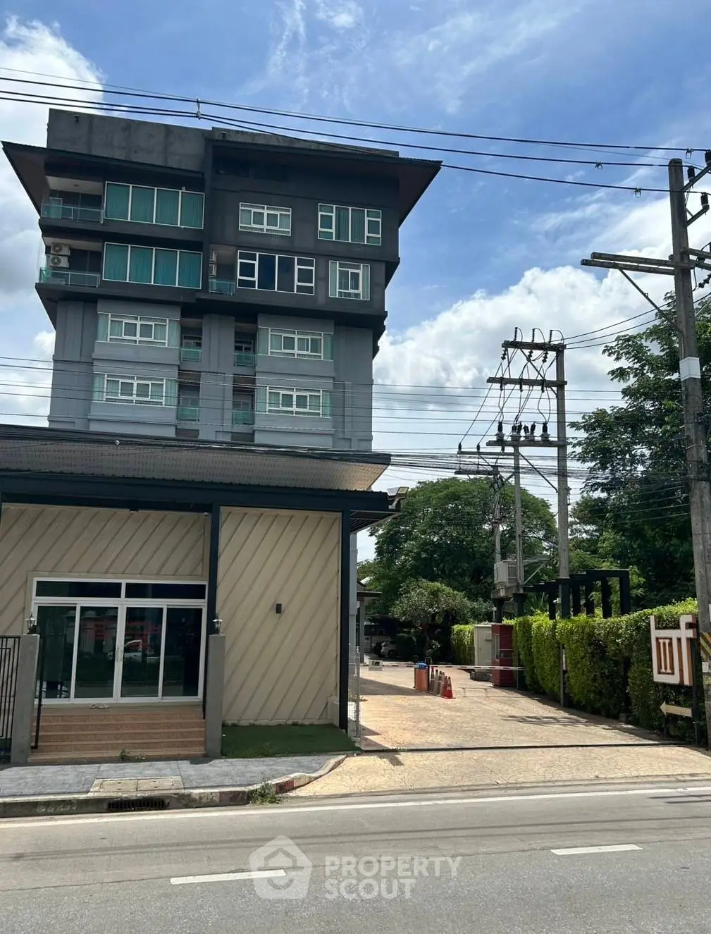 Modern multi-story building with street view and lush greenery, ideal for urban living.