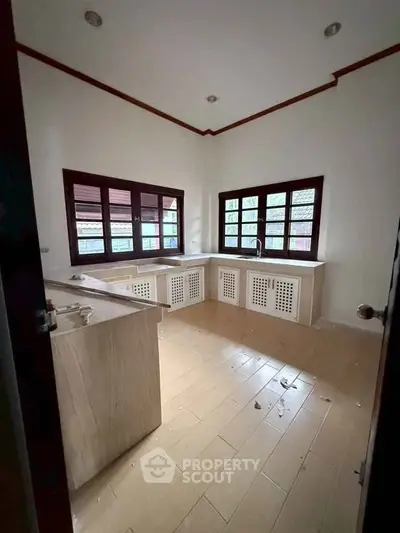 Spacious kitchen with large windows and wooden cabinetry in a modern home.