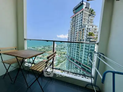 Stunning balcony view with modern high-rise building and ocean backdrop, perfect for relaxation.
