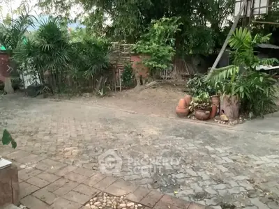 Charming garden area with lush greenery and rustic pavers, perfect for outdoor relaxation.
