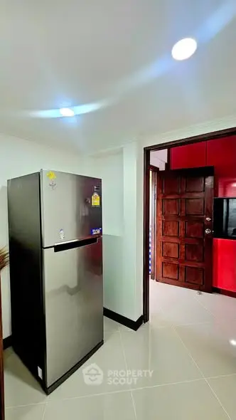 Modern kitchen with stainless steel fridge and red cabinetry in a stylish apartment.