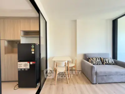 Modern living room with sleek furniture and natural light, featuring a compact dining area and stylish sofa.