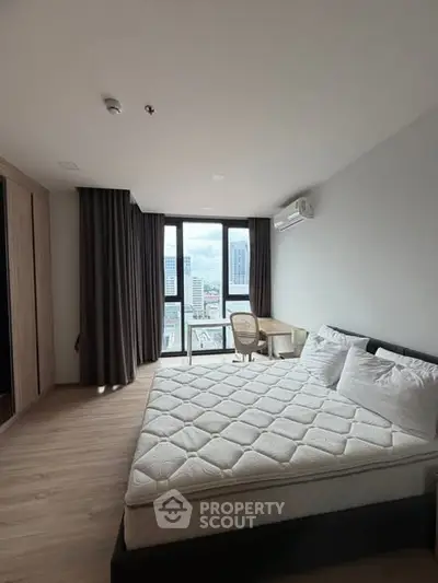 Spacious bedroom with city view, large windows, and modern furnishings in a high-rise apartment.
