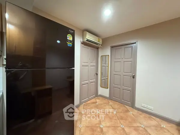 Modern kitchen with sleek black refrigerator and air conditioning unit.