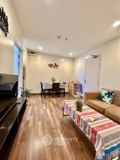 Spacious living room with wooden flooring and cozy dining area in modern apartment.