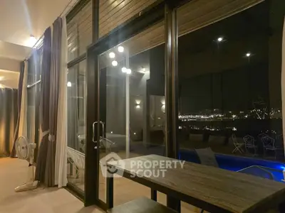 Luxurious modern living room with floor-to-ceiling windows overlooking a serene night view and pool.