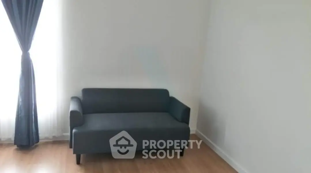 Minimalist living room with sleek gray sofa and elegant curtains, perfect for modern living.