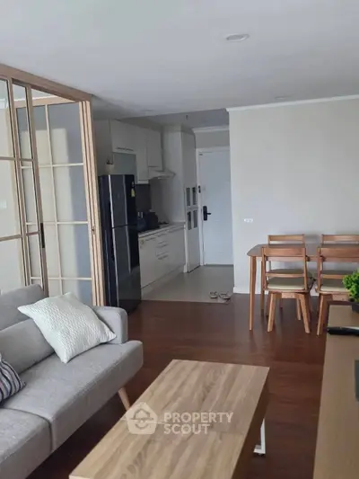 Modern open-plan living room with kitchen, featuring sleek furniture and wooden accents.