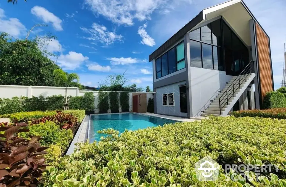 Modern house with pool and lush garden under clear blue sky