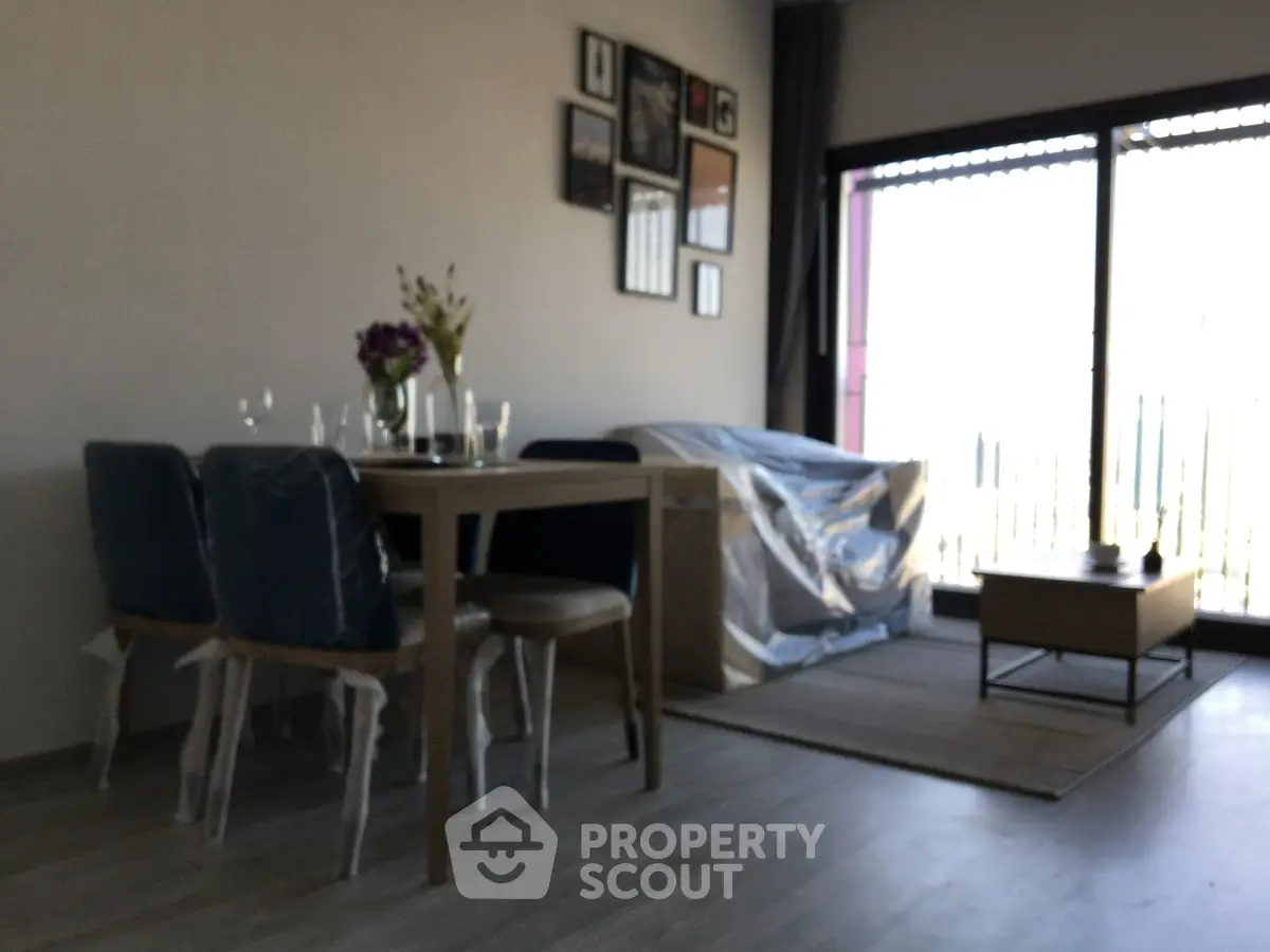 Modern living room with dining area and balcony access, featuring stylish decor and natural light.