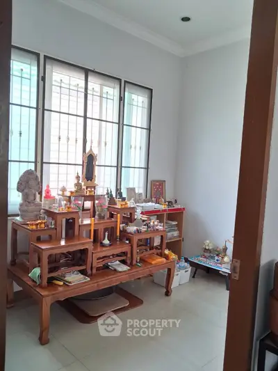 Cozy room with large window and wooden shelves, perfect for a serene home sanctuary.