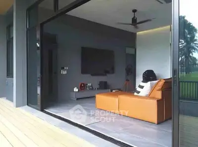 Modern living room with sleek design and large glass sliding doors opening to a balcony.