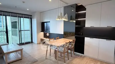 Modern open-plan living room with dining area and large windows in a stylish apartment.