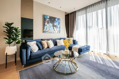 Luxurious modern living room with elegant blue sofa, stylish decor, and abundant natural light.