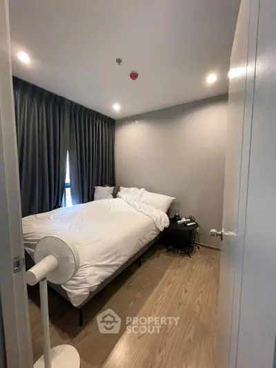 Cozy bedroom with modern decor and wooden flooring, featuring a comfortable bed and stylish curtains.