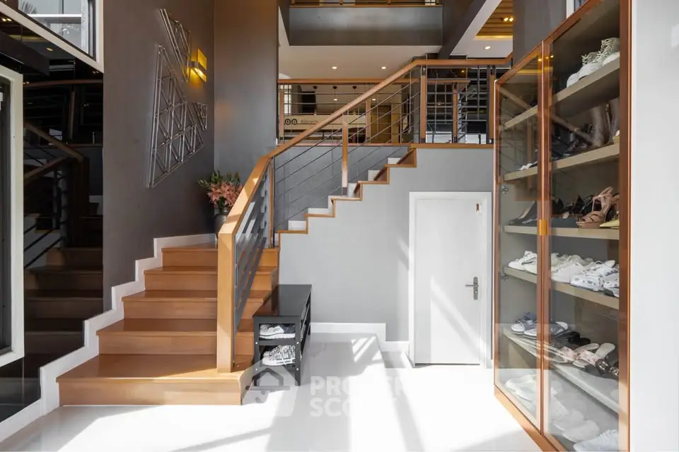 Modern interior with stylish staircase and shoe display in bright entryway