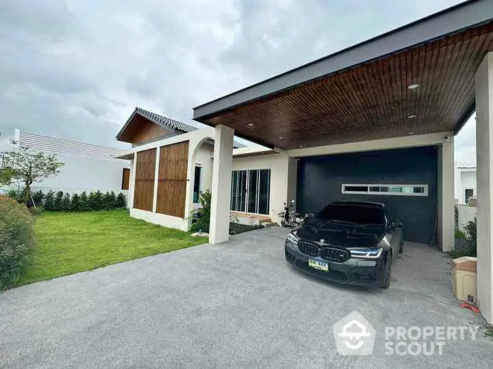 Modern house with sleek carport and luxury vehicle, showcasing contemporary architecture and spacious driveway.