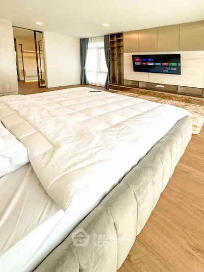 Luxurious bedroom with modern decor and large TV, perfect for relaxation.