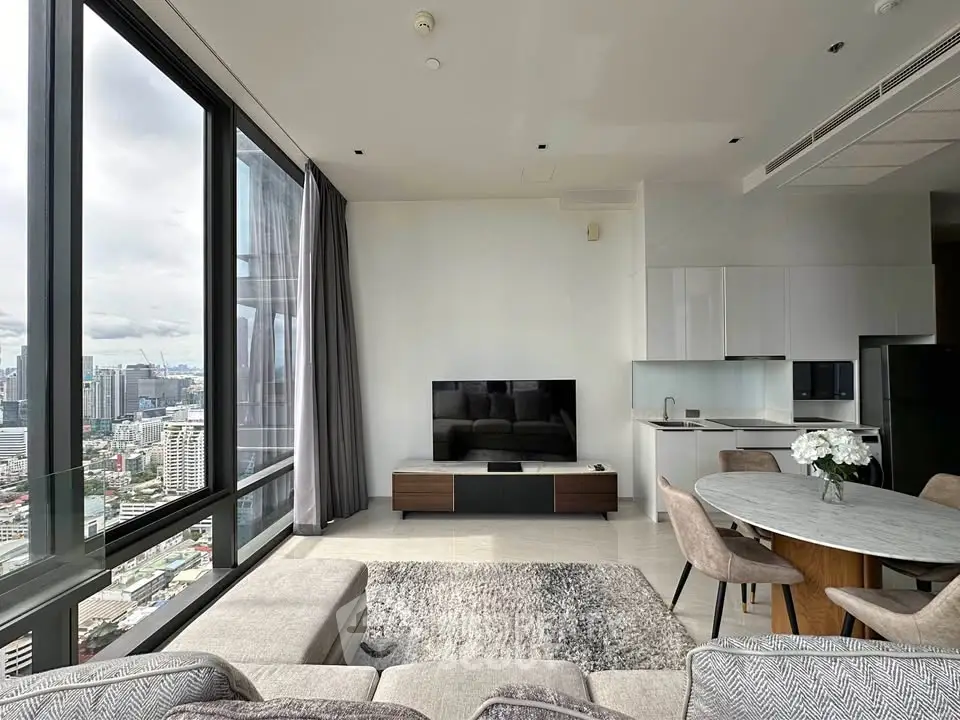 Luxurious high-rise living room with panoramic city views and modern open kitchen.