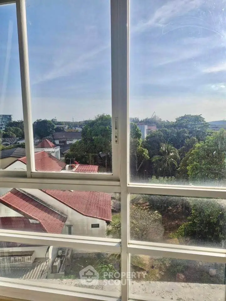 Stunning view from a window overlooking rooftops and lush greenery.