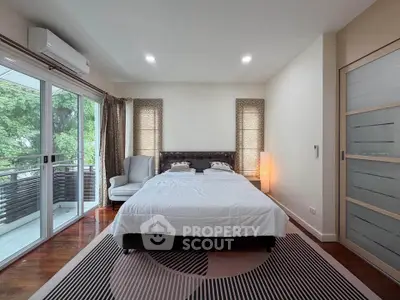 Spacious bedroom with large windows and balcony access, featuring modern decor and ample natural light.