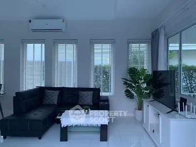 Modern living room with sleek black sofa, large windows, and stylish decor.