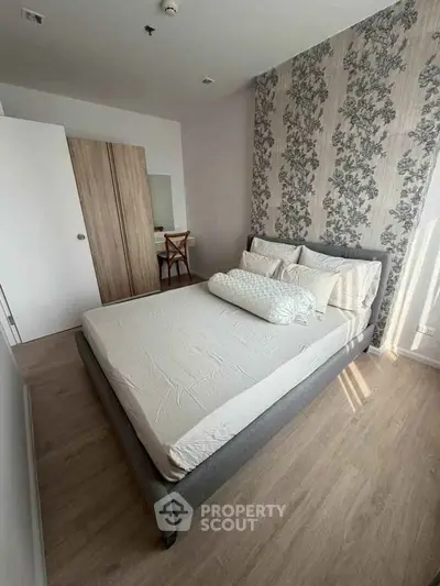 Cozy bedroom with stylish wallpaper and natural light, perfect for relaxation.
