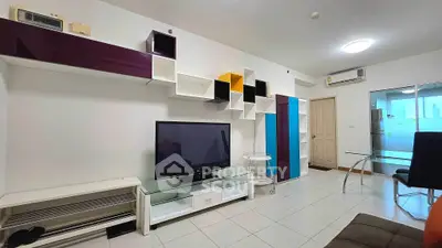Modern living room with stylish shelving and flat-screen TV, featuring sleek furniture and bright lighting.
