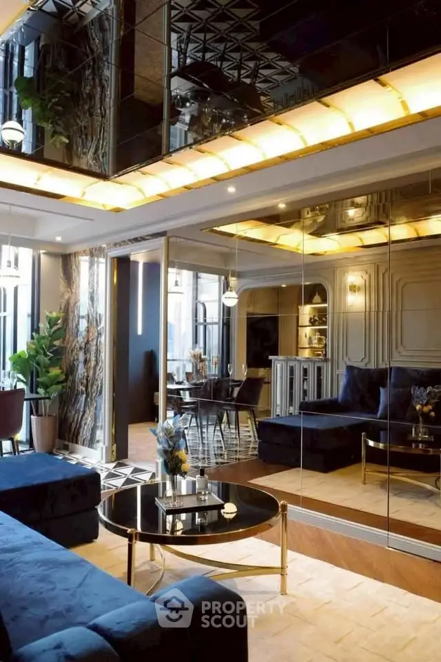 Luxurious living room with mirrored walls and elegant decor, featuring plush blue sofas and a chic coffee table.