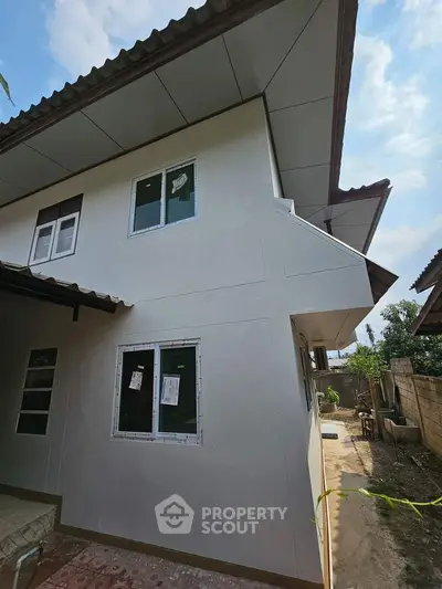Newly constructed two-story home with a modern design, featuring crisp white exterior walls and multiple windows for ample natural light, set in a developing neighborhood.
