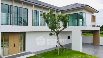 Modern two-story house with large windows and lush green lawn, showcasing contemporary architecture.