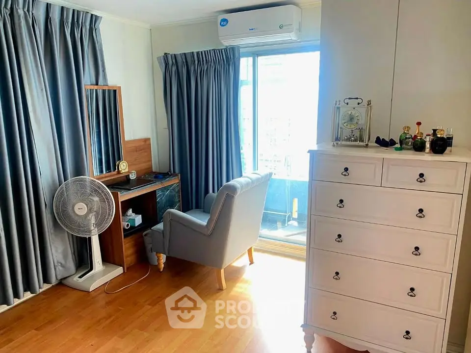 Cozy bedroom with elegant dresser and balcony access, featuring a comfortable armchair and stylish decor.