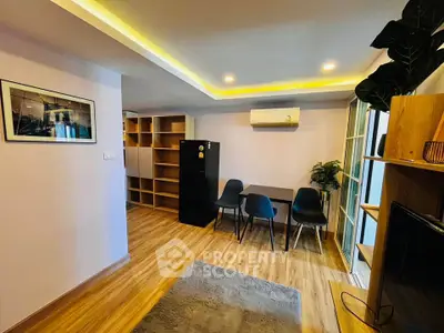 Modern living room with stylish furniture and ambient lighting, featuring a sleek black refrigerator and dining area.