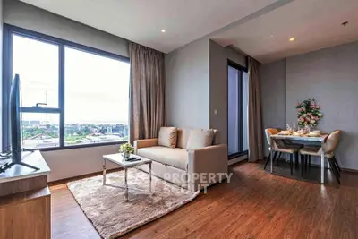Modern living room with cozy sofa and dining area, featuring large window with city view.