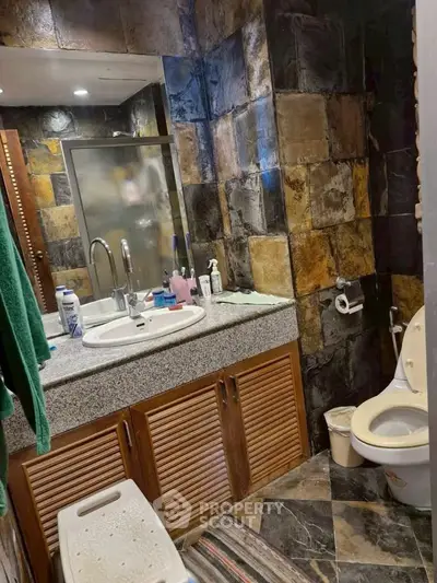 Stylish bathroom with stone tile walls and modern fixtures in a contemporary home.