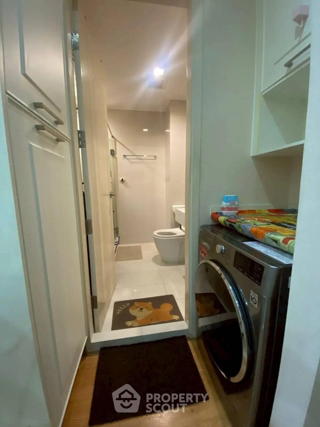Compact bathroom with washing machine and storage cabinets in modern apartment.