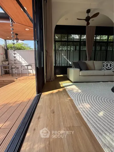 Stylish living room with wooden flooring and large windows opening to a spacious deck.