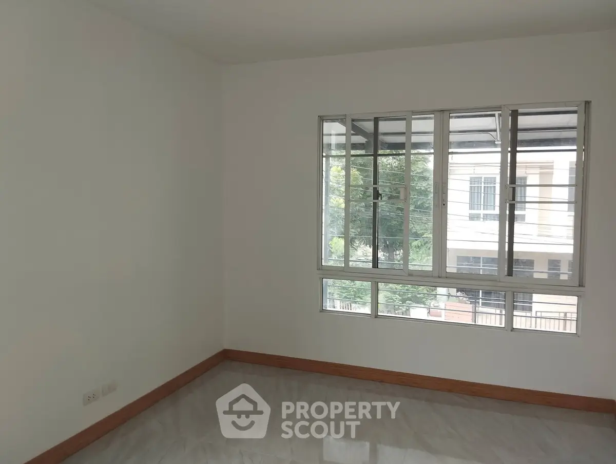 Spacious empty room with large window and polished floor, ideal for customization.