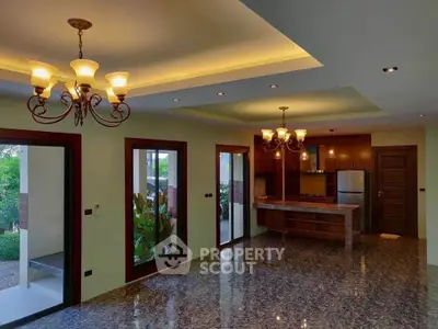 Spacious living room with elegant lighting and garden view, featuring modern kitchen area and glossy flooring.