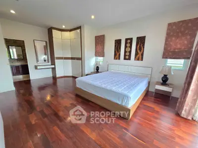 Spacious bedroom with wooden flooring and modern decor in a luxury home.