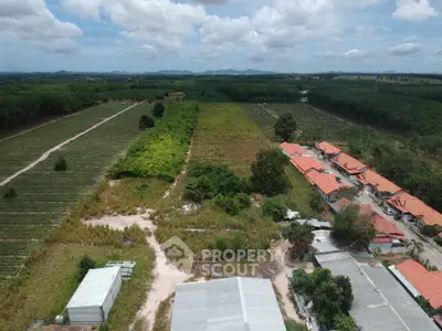 Aerial view of expansive rural land with red-roofed buildings and lush greenery, perfect for development.