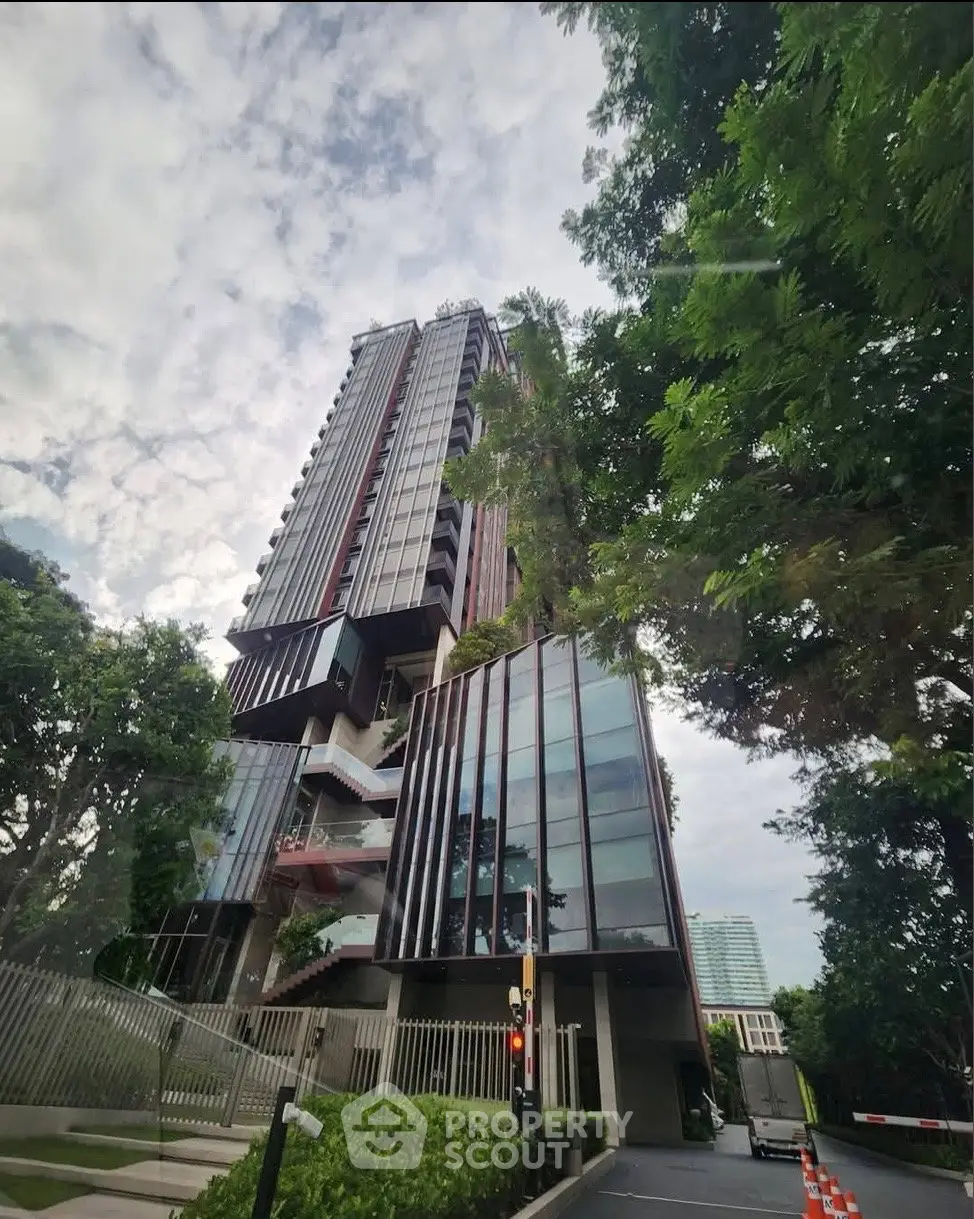 Modern high-rise building with lush greenery and sleek architectural design.