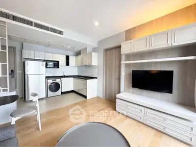 Modern living room with open kitchen, featuring sleek appliances and stylish decor.