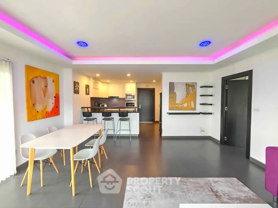 Modern open-plan living room with stylish kitchen and vibrant lighting