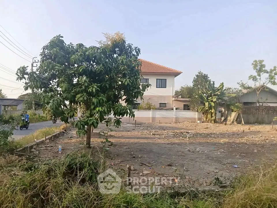 Spacious plot of land with a modern house and lush greenery, ideal for development opportunities.