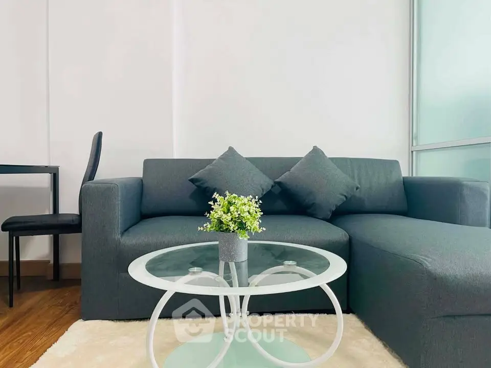 Modern living room with stylish gray sofa and glass coffee table in a cozy apartment.